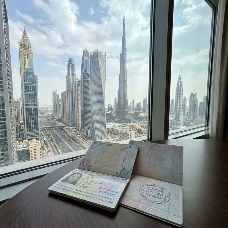 Passport with Dubai visa stamp open on desk against Dubai city skyline